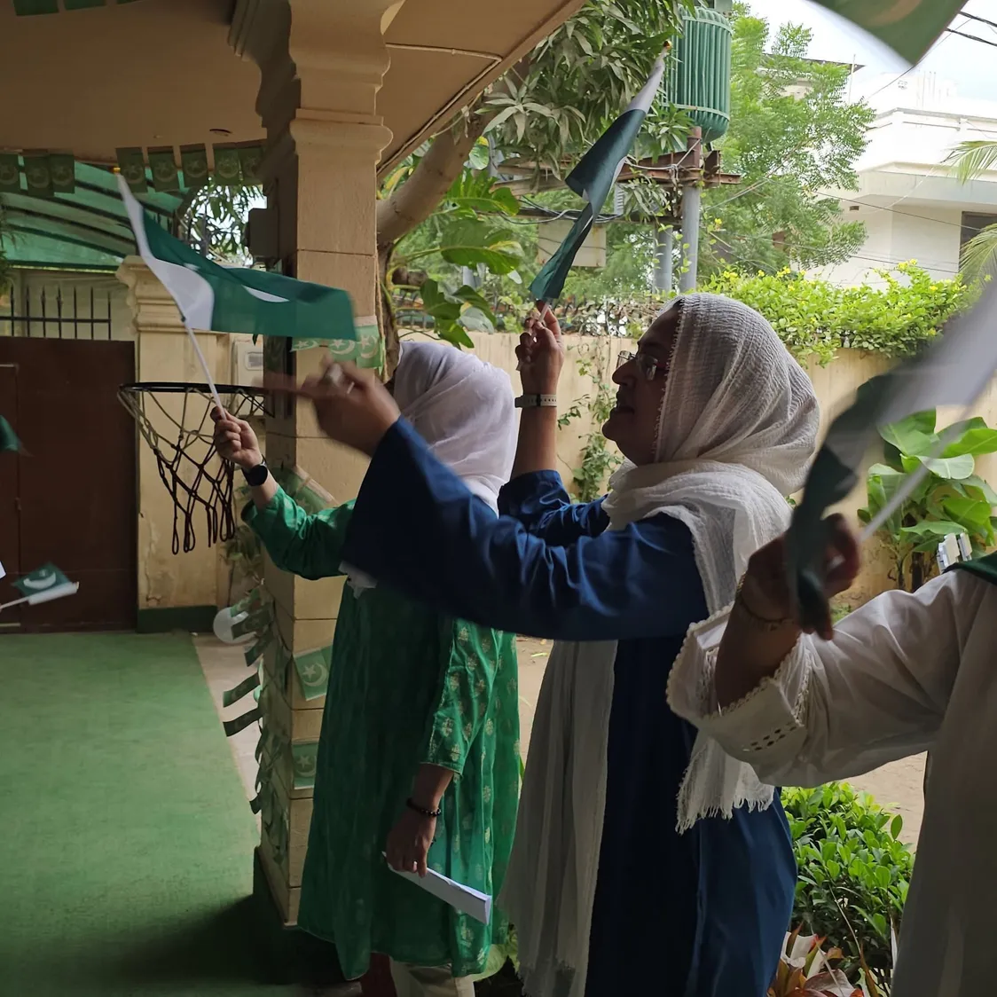 Spring Buds teachers raise Pakistan flags on the school porch on Independence Day